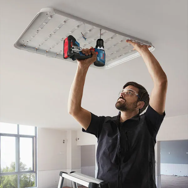 GSR 18V-65 A person wearing safety equipment uses a power drill to install a ceiling light fixture.