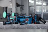 Cordless polishing and sanding tools with blue storage case on a workbench in a workshop.