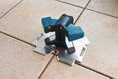 Tile laser leveling tool with three adjustable arms for precise alignment.