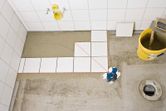 Laser leveling tool projecting lines on floor tiles.