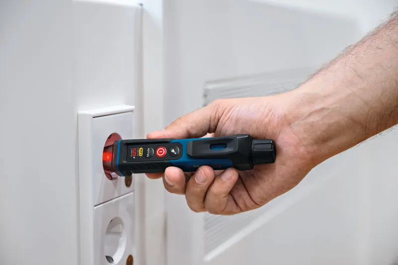 A person uses a non-contact voltage tester near an electrical socket.