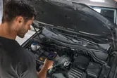 Person inspects a car engine using a thermal camera.