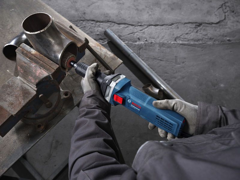 GGS 5 LS A person wearing safety equipment grinds the inside of a metal pipe with a straight grinder.