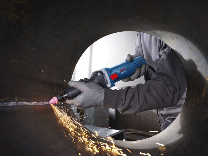 GGS 5 LS A person wearing safety equipment uses a straight grinder to smooth the inside of a metal pipe.
