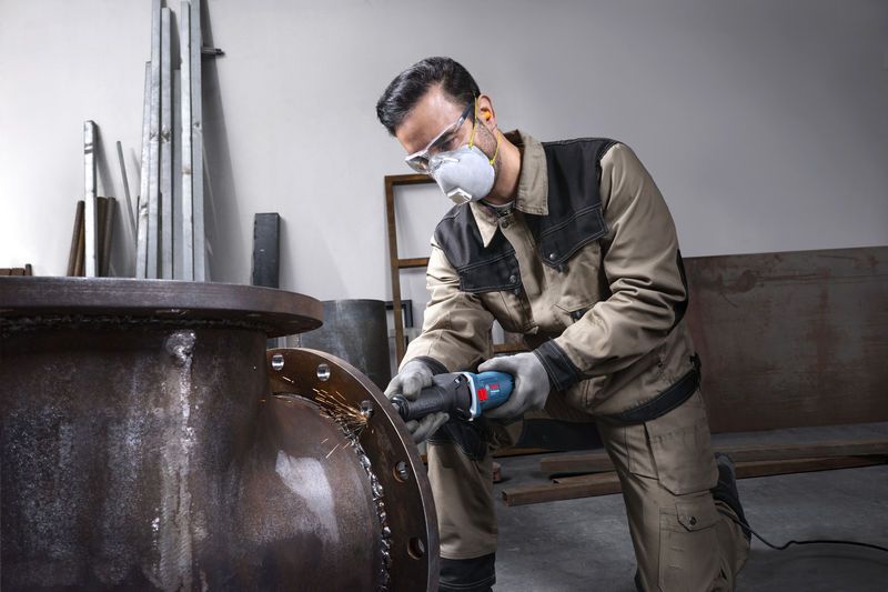 GGS 5 LS A person wearing safety equipment grinds the edge of a large metal pipe.