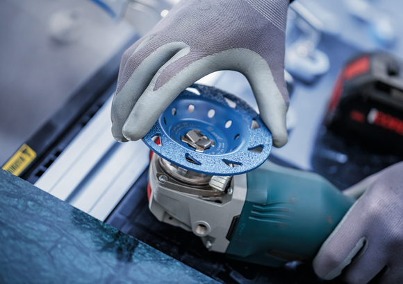Person wearing safety equipment attaches a grinding disc to a power tool.