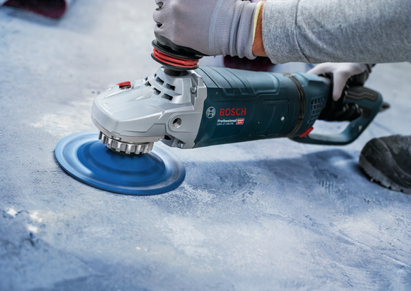 A person wearing safety equipment polishes a concrete floor with a power tool.