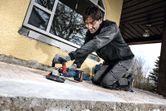 A person wearing safety equipment grinds a concrete surface with a power tool.