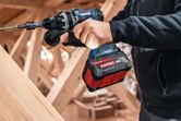 A person driving a screw into wood with a cordless drill.
