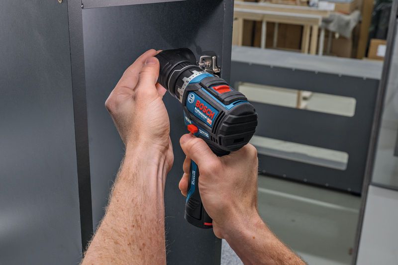 Person uses a cordless screwdriver to drive a screw into a metal panel.