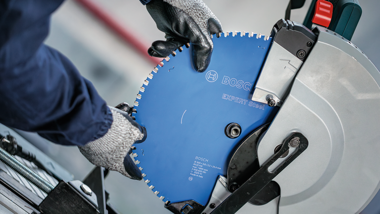 EXPERT Steel Circular Saw Blade, 305 x 2.6/2.2 x 25.4 mm, T60 Person wearing safety equipment installs a circular saw blade onto a cut-off machine.