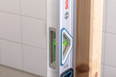 Spirit level measuring the vertical alignment of a wooden post.