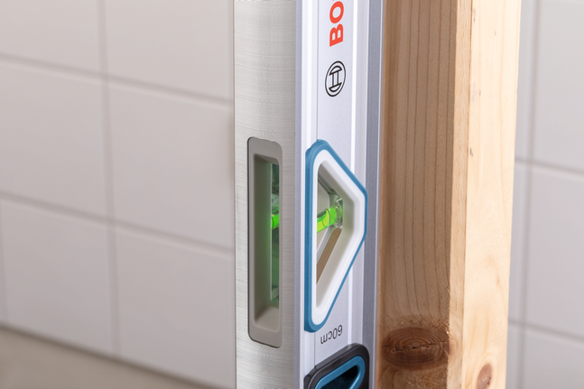 Spirit level checking vertical alignment of a wooden post.
