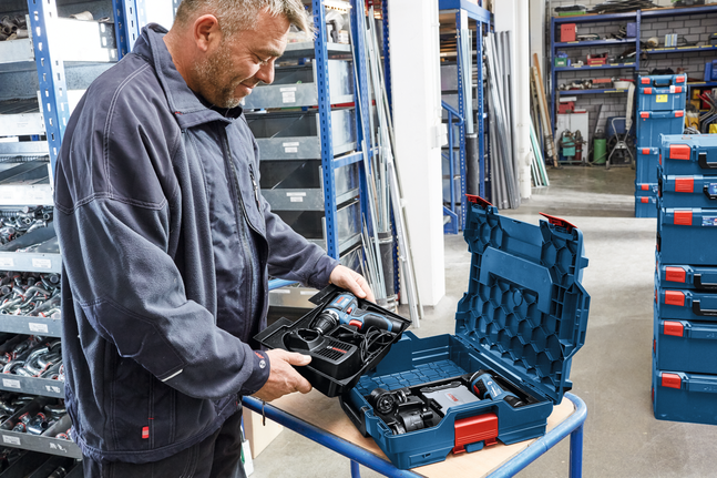 Person inspects a cordless drill kit in a workshop.