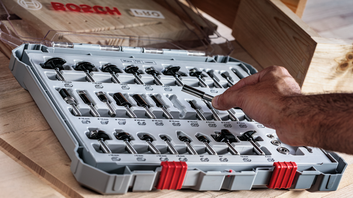 Object #200587568: 7437800_app_web_03 Person selecting a router bit from an organized case on a wooden table.