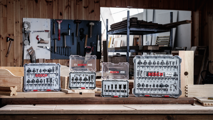 Object #200587570: 7437800_app_web_05 Router bit sets displayed on a wooden workbench in a carpenter’s workshop.