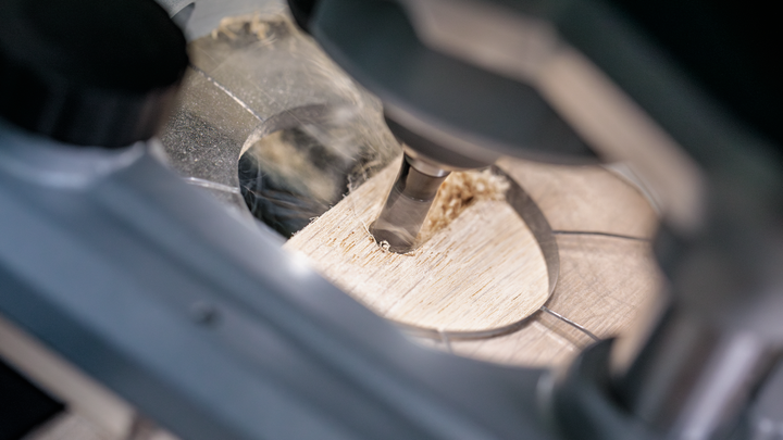 Drill making a precise circular cut through a wooden board.