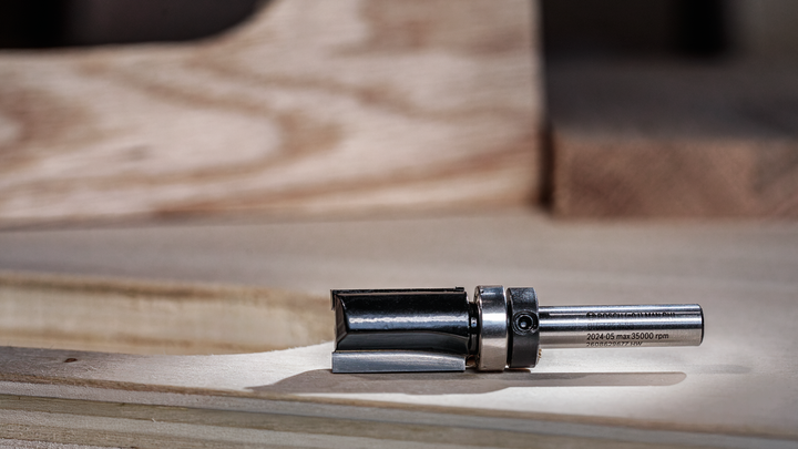 Metal router bit resting on a wooden work surface.