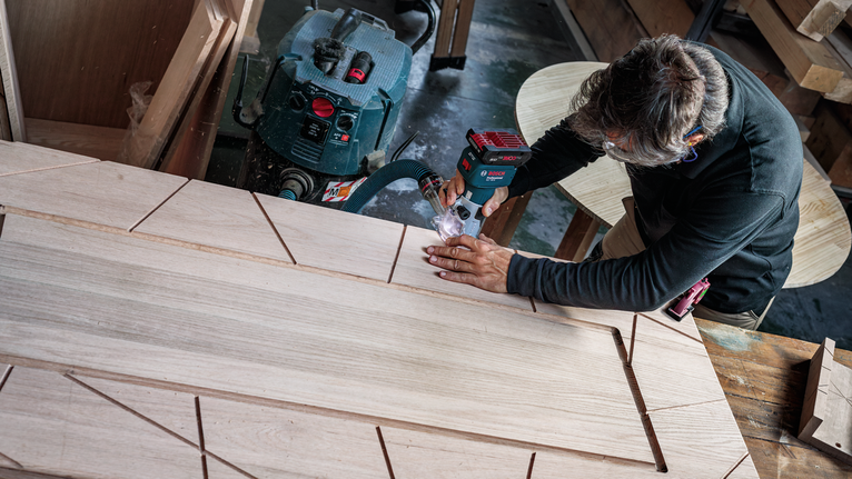 PRO Router Bit Rounding Over, R 1/4″, Shank 1/4″ Person cutting geometric patterns into wood with a power tool in a workshop.
