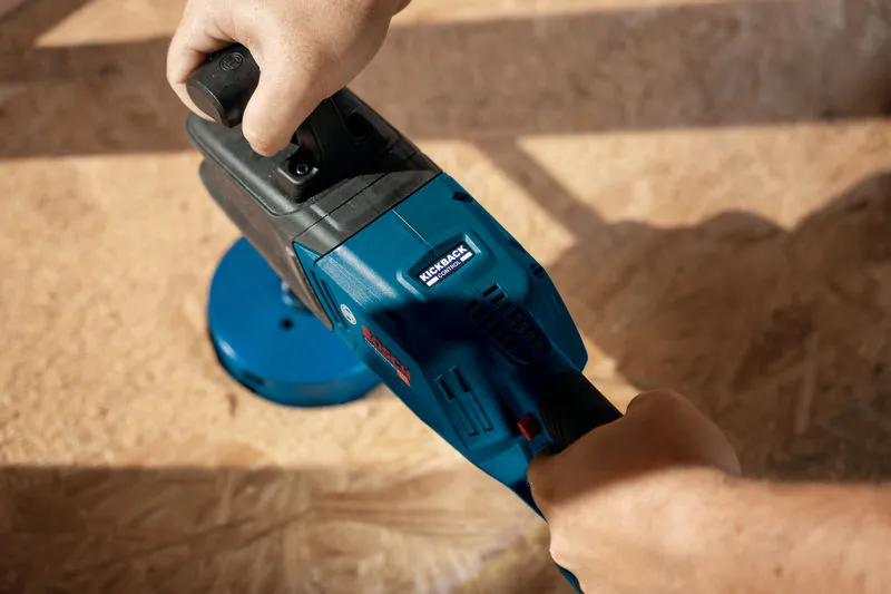 A person operates a blue cordless angle drill on a wooden surface.