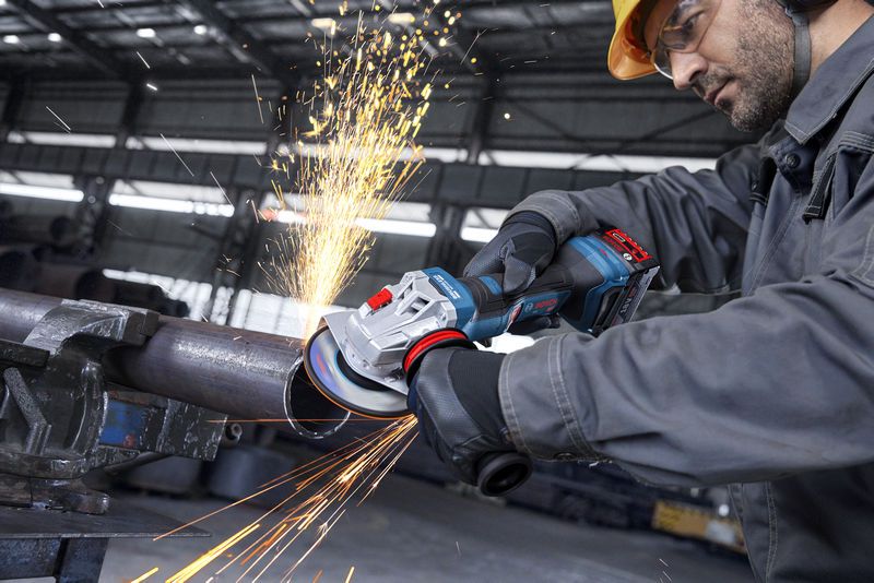 GWS18V-11PS A person wearing safety equipment grinds a metal pipe with an angle grinder.