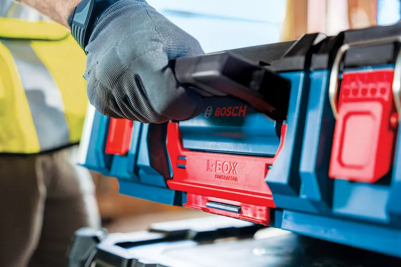A person wearing safety equipment lifts a blue and red carrying case system.