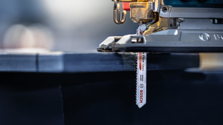 Jigsaw cutting through a sheet of laminated wood.