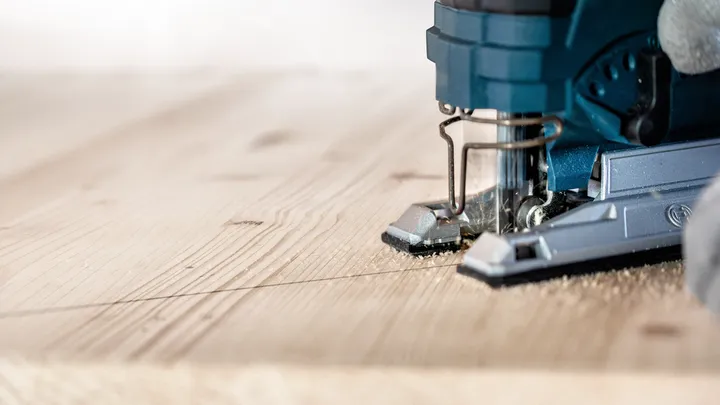 Object #200597867: 2793296_app_web_01 Person guides a jigsaw along a marked line cutting a wooden plank.