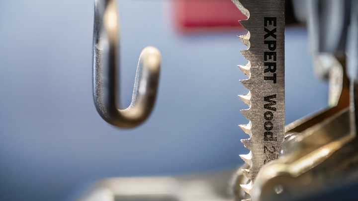 Object #200597876: 2793297_app_web_02 Close-up of a jigsaw blade labeled for wood cutting attached to a power tool.