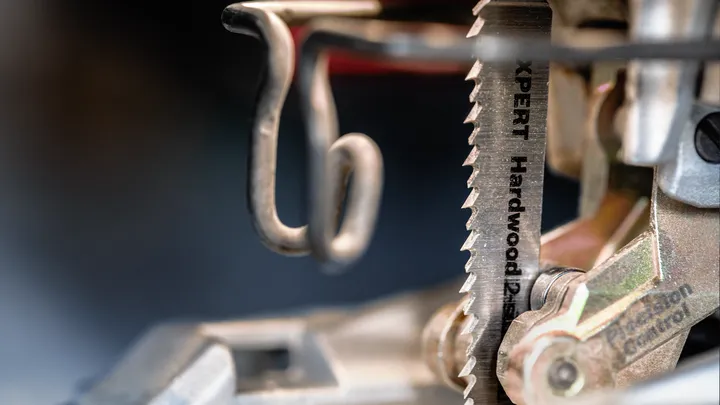 Object #200597889: 2793295_app_web_04 Close-up of a hardwood saw blade mounted in a jigsaw under workshop lighting.