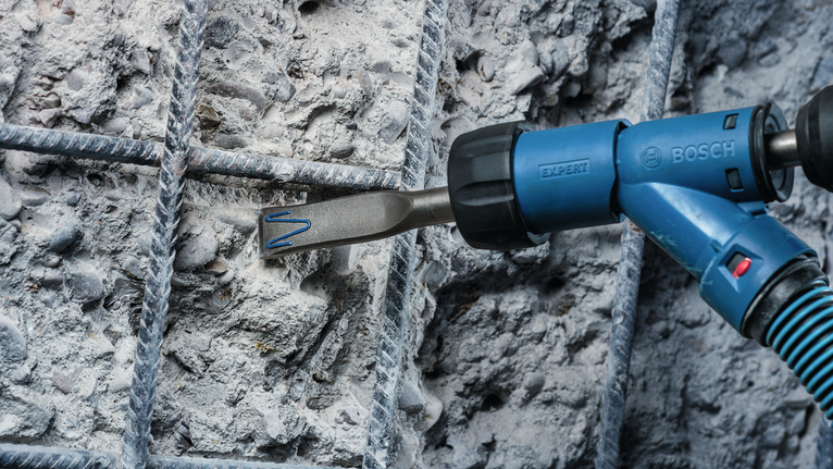 Power tool breaking concrete between metal rebar.