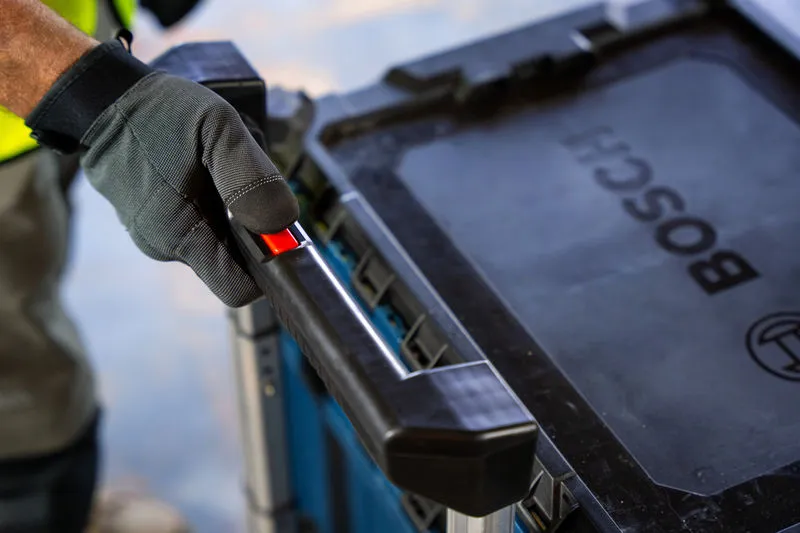 A person wearing safety equipment grips a carrying case system handle.
