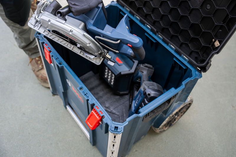 A person places a circular saw into a carrying case system on a construction site.