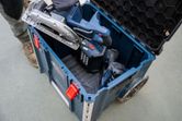 A person places a circular saw into a carrying case system on a construction site.