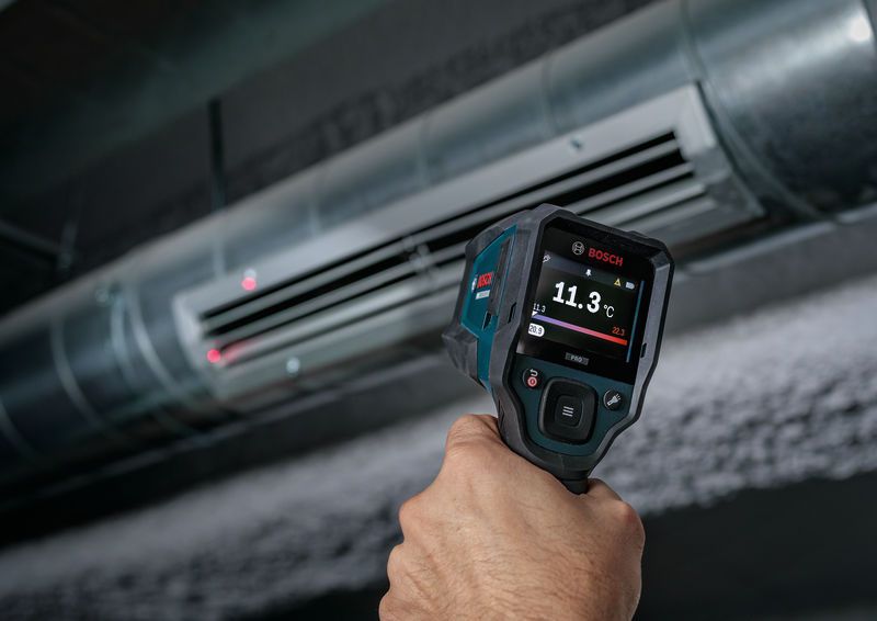 Person using a thermo detector to measure air temperature at an HVAC vent.