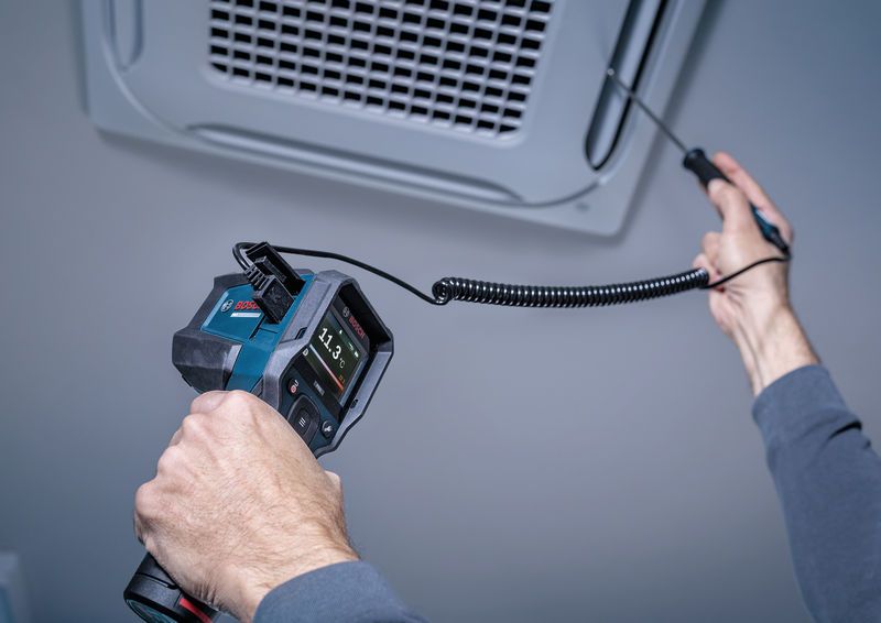 A person uses a thermo detector to measure temperature at an air vent.