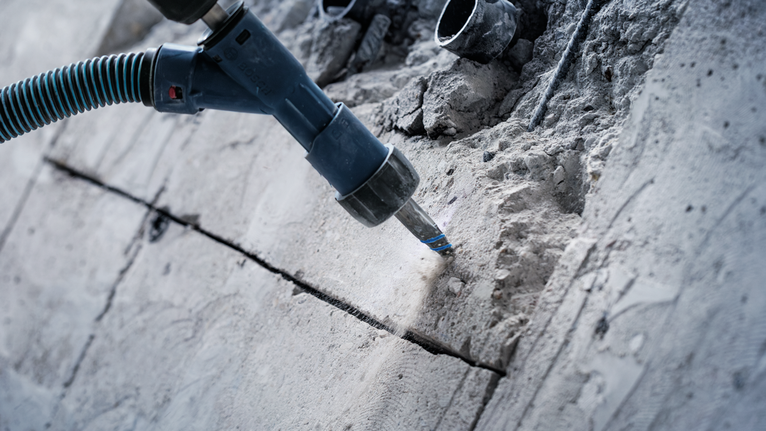 Rotary hammer drilling a groove into a concrete wall.