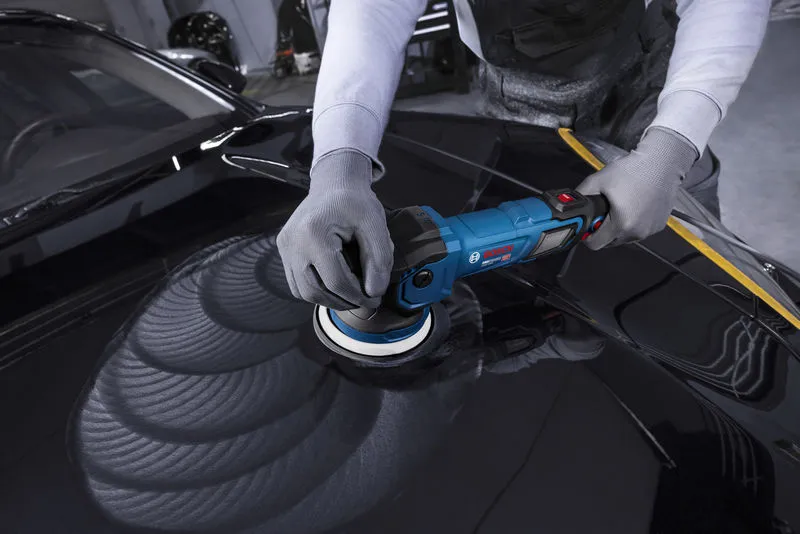 A person wearing safety equipment polishes a car hood with a blue polisher.