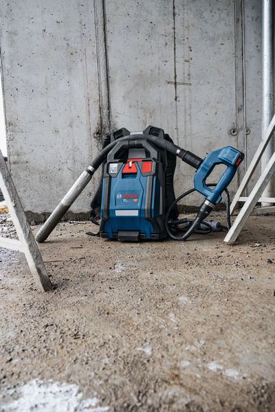 Cordless backpack dust extractor resting on a construction site floor.