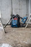 Cordless backpack dust extractor resting on a construction site floor.