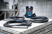 Concrete vibration tools with long black hoses and a control unit placed on a metal surface.