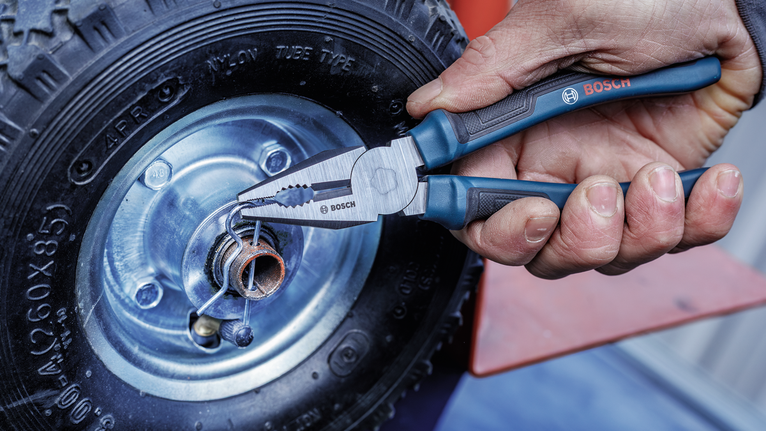 Person uses pliers to adjust a metal part on a wheel.