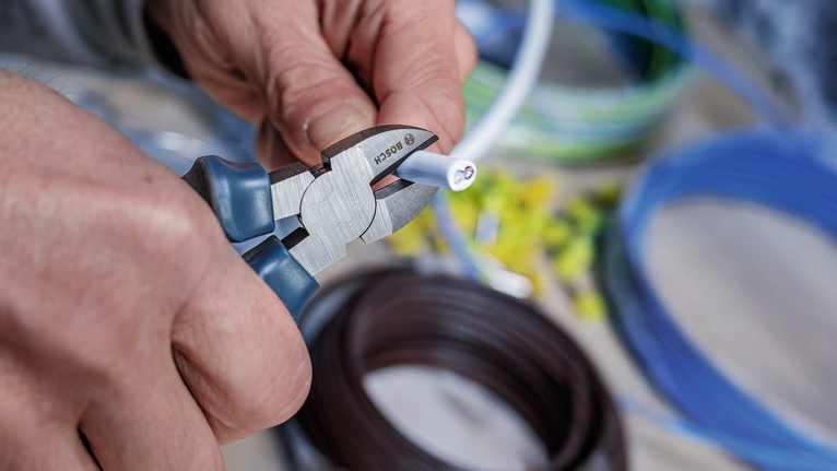 Person cuts an electrical cable with pliers.