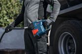 A person wearing safety equipment refuels a truck using a portable pump.