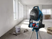 Portable jobsite fan on a tripod cooling an unfinished room with sunlight streaming in.