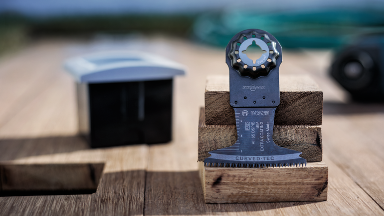 Oscillating multitool cutting blade resting on stacked wooden blocks.