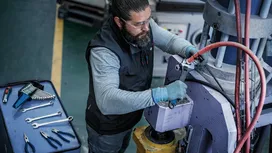 Person wearing safety equipment tightens bolts on industrial machinery.