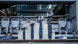 Four adjustable wrenches of different sizes are lined up on concrete blocks in a workshop.