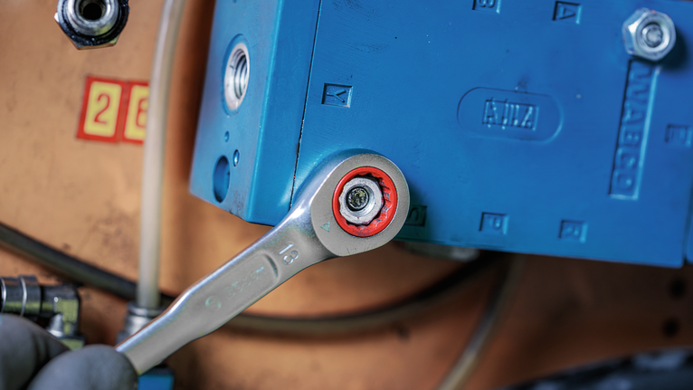 A wrench tightens a bolt on industrial machinery.