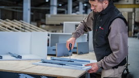 Person assembling drawer slides with a screwdriver in a workshop.